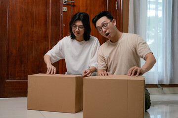 couple stand by a large cardboard box near a wooden door with a fresh start at new home