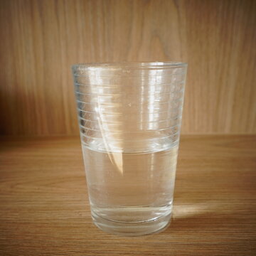 A refreshing clear glass of water sitting on a wooden surface