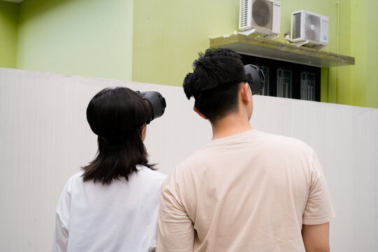 couples wear VR headsets in a sunny urban backyard, exploring immersive visuals together