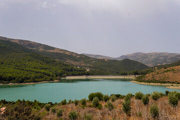 Fototapeta premium Scenic view of a turquoise lake surrounded by green mountains near Chefchaouen, Morocco. A peaceful nature and travel destination