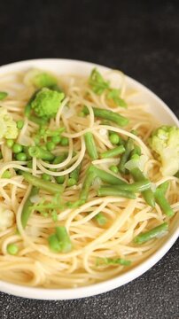 Spaghetti vegetables green peas, broccoli, string beans, kohlrabi vegetarian pasta tasty snack fresh delicious gourmet food background on the table rustic top view copy space vegan food