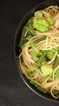 Spaghetti vegetables green peas, broccoli, string beans, kohlrabi vegetarian pasta tasty snack fresh delicious gourmet food background on the table rustic top view copy space vegan food