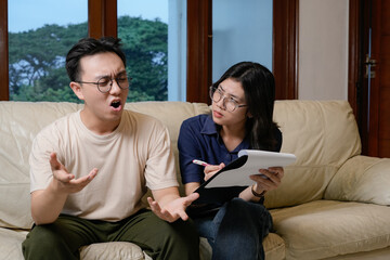 Obraz premium concerned man on sofa receives comfort from friend while reviewing paperwork at home.psychotheraphy concept