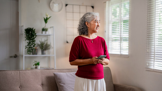 Asian senior woman home using smartphone connecting online digital communication active lifestyle technology elderly wellbeing