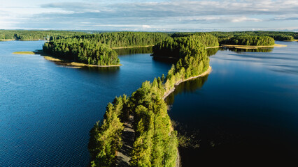Aerial view of the tranquil Punkaharju area in Finland, showcasing lush greenery and reflective waters. This scenic landscape offers a perfect retreat for nature lovers and adventure seekers.