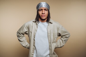 Young man with braided hair poses confidently in studio setting with neutral background