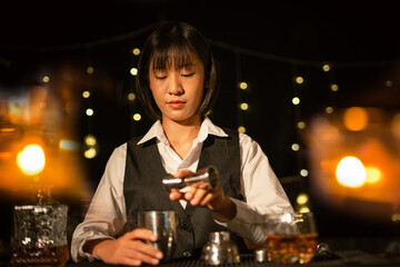 Professional female bartender preparing alcoholic drinks in a bar