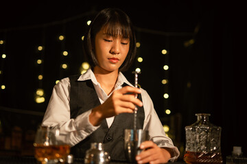Professional female bartender preparing alcoholic drinks in a bar