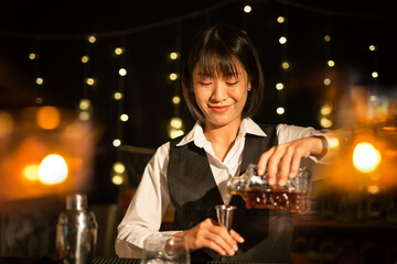 Professional female bartender preparing alcoholic drinks in a bar