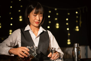 Professional female bartender preparing alcoholic drinks in a bar