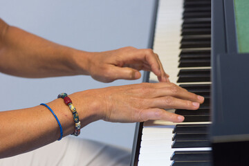 Human hands playing the keys notes and chords on a classic black piano during a pianolesson