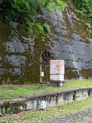苔むしたコンクリート斜面に設置された老朽化した鉄道設備