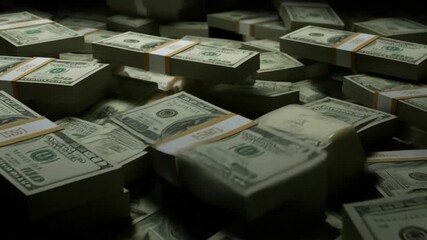 Stacks of united states currency bills and bundles arranged on a dark surface in a dim light