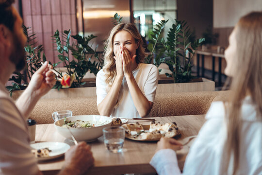 Woman laughing covering mouth during friends restaurant meal