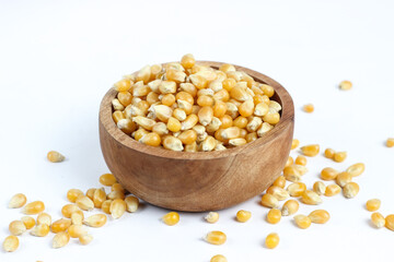 Raw corn kernels or popcorn in a small wooden bowl. Isolated on a white background.