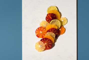 Surtido de rodajas de cítricos en  un plato de mármol blanco sobre fondo azul . Vista superior	