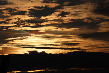 Dramatic Golden Sunset Sky with Dark Clouds Reflected on Water