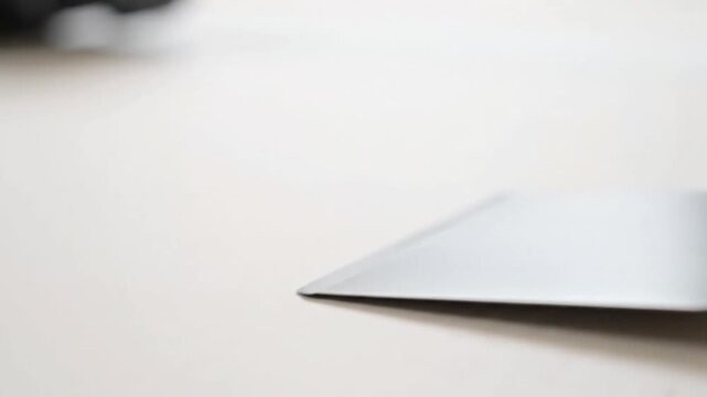 Sleek silver laptop or tablet edge resting on a bright white surface with a blurred soft focus background showcasing modern minimalist technology design and cle