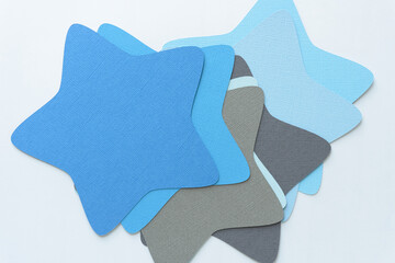 large stars machine-cut from textured blank paper squares and arranged overlapping on blank surface