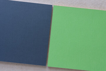 Fototapeta premium navy blue and green paper square pads on blank gray crafting paper