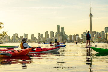 Paddlers hanging out on SUP's and sea kayaks viewing the downtown Toronto skyline from the Toronto Islands at sunset, room for text