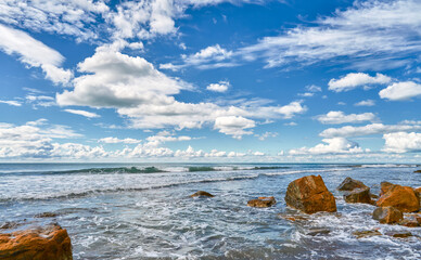 seascape featuring a stormy sea and fallen rock fragments, a horizon with cumulus clouds, a concept of turbulent elements and the power of nature, copy space for natural projects
