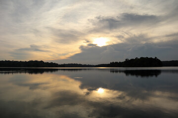 Golden sunset sky with dramatic clouds reflecting on still lake water