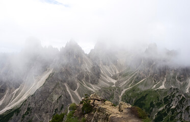 Majestic mountain peaks shrouded in mist with rocky terrain and lush greenery in the foreground