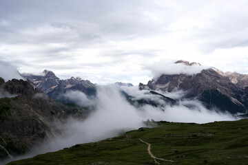 Majestic mountain landscape with clouds and mist enveloping the peaks in the Dolomites region of Italy