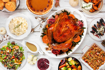 Thanksgiving turkey dinner. Overhead view table scene on a rustic white wood background. Turkey, mashed potatoes, stuffing, pumpkin pie and sides.