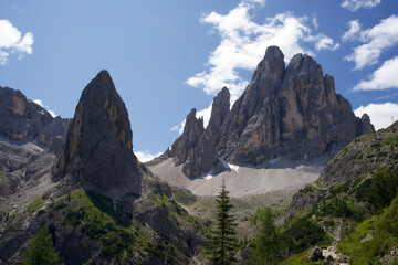 Majestic Dolomite mountains under bright blue sky with lush greenery and rocky peaks in summer landscape