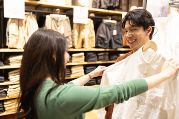 Young Asian woman choosing a shirt for her boyfriend in a clothing store malls or small shops, Shopping is everyday life concept