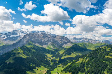 Fototapeta premium Scenic alpine landscape with green meadows, towering mountains, and clear blue summer skies in the heart of the Swiss Alps