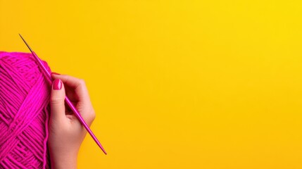 A vibrant pink yarn ball held by a hand with a crochet hook against a bright yellow background