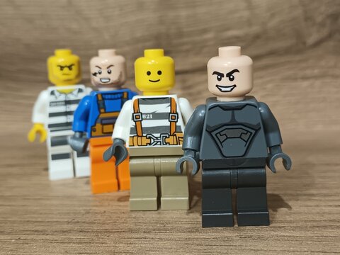 Four toy figurines in varied outfits stand in a staggered line on a wooden surface