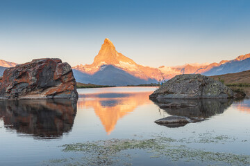 Sunrise illuminating the Matterhorn, reflected in the tranquil waters of Stellisee, creating a breathtaking alpine scene