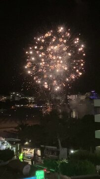 Vertical video. Fireworks on the beach celebrating the end of the fiesta. Multicolored charges rise to a low altitude with high intensity. Mallorca Island, Spain.
