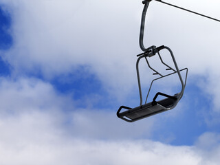 Chair-lift and blue sky with clouds