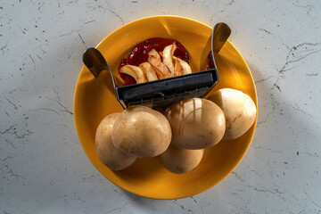 raw and fried potatoes on a yellow plate, top view