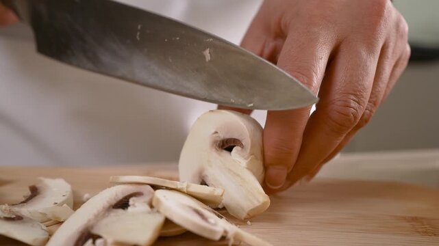 A person is cutting mushrooms on a cutting board. The mushrooms are sliced into small pieces. The person is using a knife to cut the mushrooms