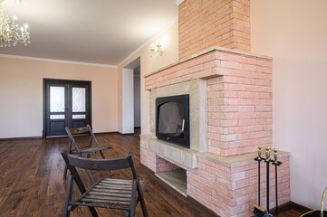 Living room with a brick fireplace, wooden floor, and two folding chairs