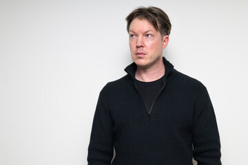 Fototapeta premium Portrait of Scandinavian mid adult man thinking in black sweater against white background