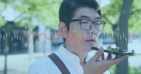 Asian man dictating message into smartphone in button-down shirt and glasses in park, chart overlay