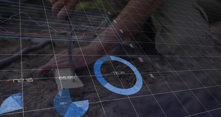 Gripping gardener's hands pressing metal dibber into loose soil at garden bed, with data overlays