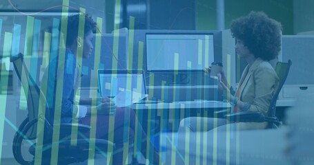 Collaborating coworkers analyzing data charts at office desk, with laptops, monitor and coffee cup