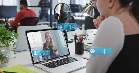 Office worker focusing on laptop call with floating notifications at desk with lamp, copy space
