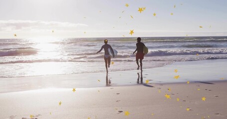 Couple in rash guard, swim trunks running toward ocean at beach, with surfboards and golden stars