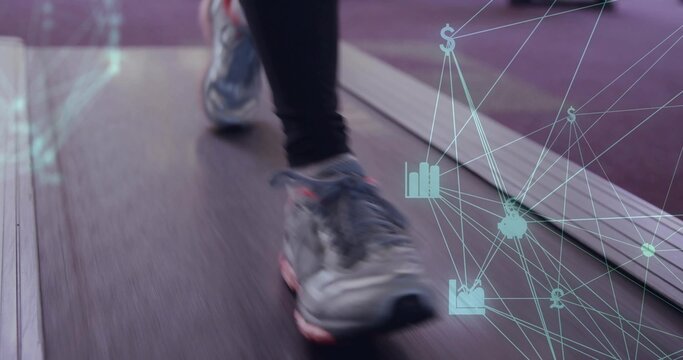 Fototapeta Moving legs wearing running shoes on treadmill belt at gym, with digital overlay of financial icons
