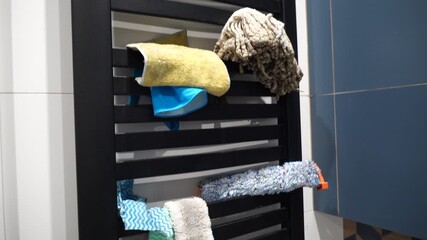 Cleaning supplies neatly organized on a heated towel rack, including sponges, cloths, and squeegees
