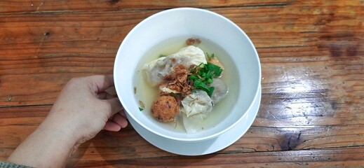 Bakso malang served in a white bowl on wooden table. Indonesian food dish